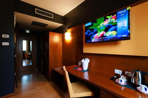 a hotel room with a desk with a television on the wall at Hotel Villa Delle Rose - Malpensa in Oleggio