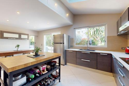 Il comprend une cuisine équipée d'un réfrigérateur et d'un comptoir avec des bouteilles de vin. dans l'établissement Villa La Roche aux Mouettes FSHH, à Nice