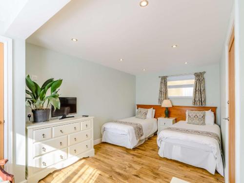 a bedroom with two beds and a dresser with a tv at 2 Bed in Langtoft 82338 in Weaverthorpe