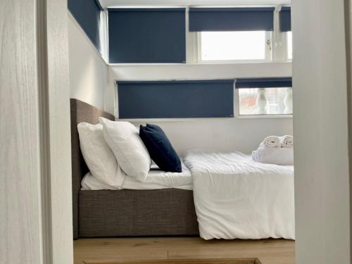 - une chambre avec un lit doté de draps et d'oreillers blancs dans l'établissement Modern flat & balcony in historic West Kensington, à Londres