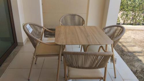 a wooden table with four chairs around it at Hawana salalah Apartment Acacia in Salalah