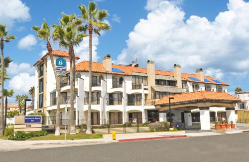 a large white building with palm trees in front of it at Huntington Beach Inn in Huntington Beach