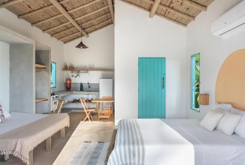 a bedroom with two beds and a kitchen in the background at Vila da Falésia in Corumbau