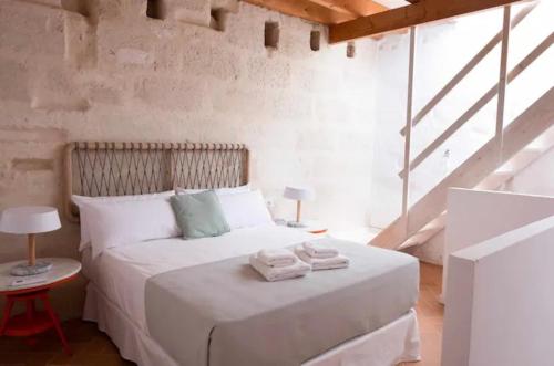 um quarto com uma cama branca e toalhas em Atico em Maó