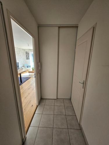 une chambre vide avec une porte et un couloir carrelé dans l'établissement L'hippique - Parking - vue Pyrénées - Balcon, à Pau