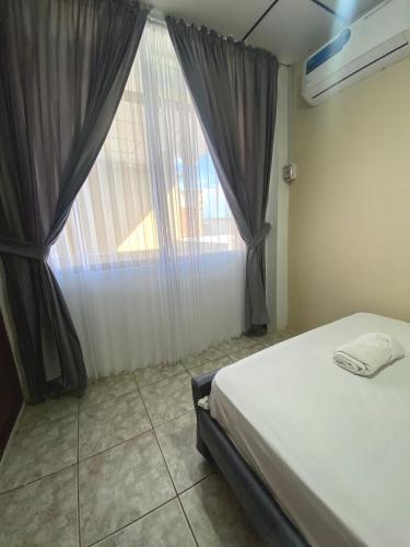 a bedroom with a bed and a large window at Moderno, grande, amplia vista, parqueo in Machala