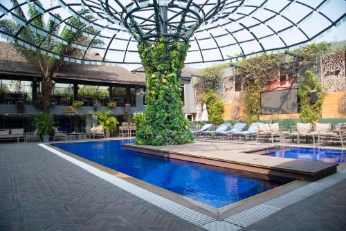 una piscina en un edificio con techo de cristal y un árbol en The Blowfish Hotel en Lagos
