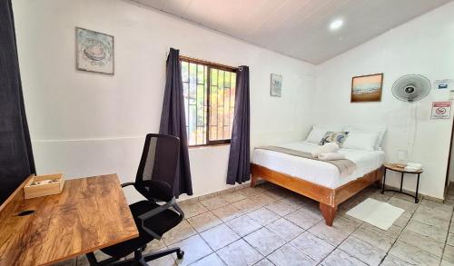 a bedroom with a bed and a desk and a window at Oceanic Playa Matapalo in Matapalo