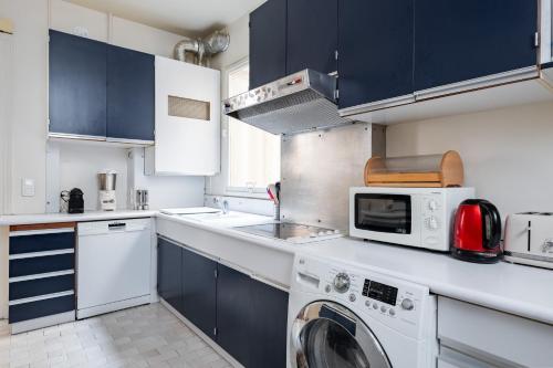 une cuisine avec un lave-linge et un micro-ondes dans l'établissement Veeve - Clichy Couture, à Paris