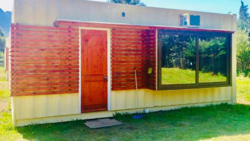 ein Haus mit einer roten Tür und einem Fenster in der Unterkunft Cabañas Céntricas 2 in Pucón