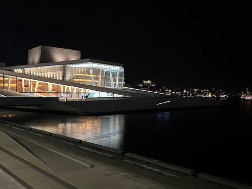 a building with a bridge over a river at night at Cozy apartment by Opera house in Oslo