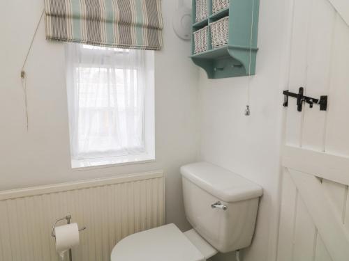 a white bathroom with a toilet and a window at Little Barber in Reading