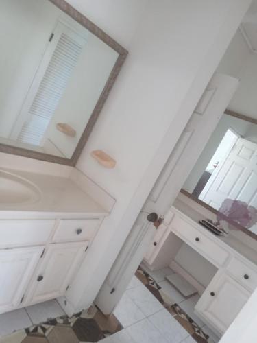 a bathroom with white cabinets and a mirror at OCEANView in Montego Bay