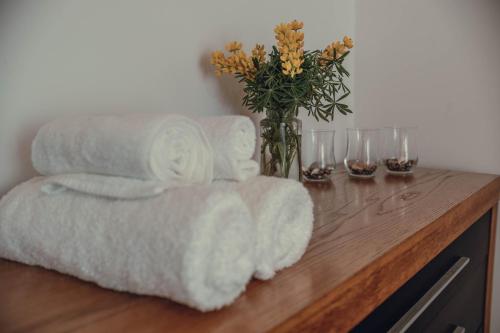 a wooden table with towels and a vase with flowers at SHR House in Porto Formoso