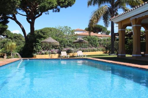 a large swimming pool with two chairs and umbrellas at Villa El Higueral in Marbella