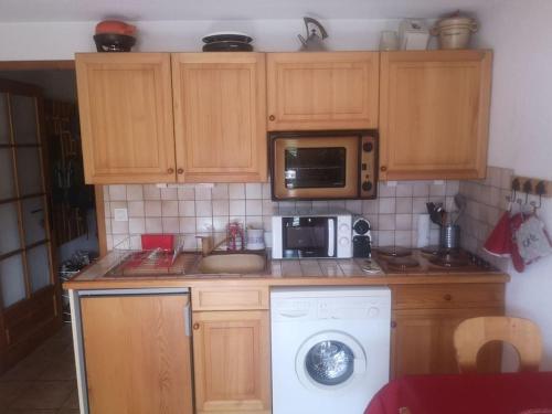 - une cuisine avec des placards en bois et un lave-linge dans l'établissement Studio cabine 4 personnes, votre refuge montagnard, à Saint-Gervais-les-Bains