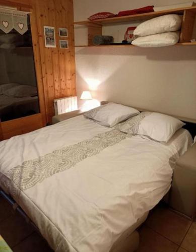 une chambre avec un grand lit avec des draps et des oreillers blancs dans l'établissement Studio cabine 4 personnes, votre refuge montagnard, à Saint-Gervais-les-Bains