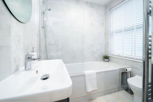 a white bathroom with a tub and a sink at Charming Granby Flat in Harrogate