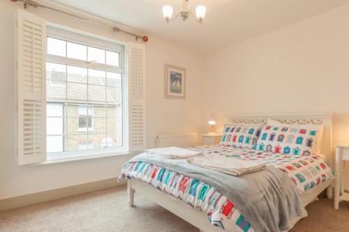 a white bedroom with a bed and a window at The Roost in Whitstable