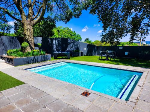 una piscina en un patio con un árbol en No Loadshedding Fast WiFi Lux Apartment en Johannesburgo