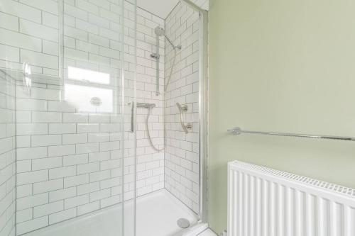 a white bathroom with a shower with a glass door at Tideway in Whitstable