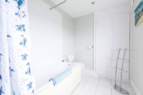 Baño blanco con bañera y cortina de ducha en Victoria Cottage, en Whitstable