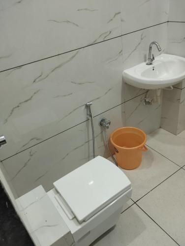 a white bathroom with a toilet and a sink at Hotel anand shree in Hoshangābād