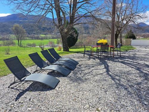 un groupe de chaises et une table dans un champ dans l'établissement APPARTEMENT BEAU SOLEIL, à La Bâtie-Neuve