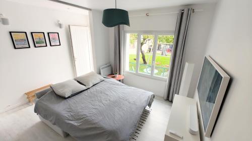 une chambre avec un lit et une grande fenêtre dans l'établissement Studio avec jardin entre Paris Versailles et gares, à Chaville