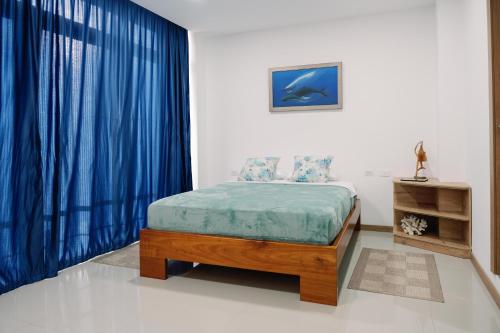 um quarto com uma cama com cortinas azuis em Modernas Habitaciones em Puerto Ayora