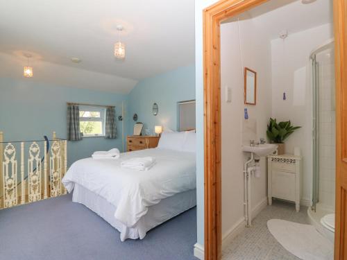 a bedroom with a white bed and a sink at Bryn Cyttun in Pwllheli