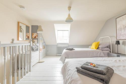 a white bedroom with two beds and a staircase at White Cottage in Whitstable