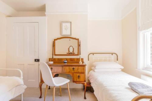 a bedroom with a desk and a mirror and a bed at Goldfinch Cottage in Whitstable