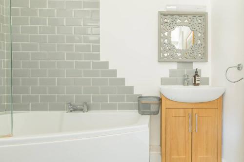 a bathroom with a sink and a bath tub and a mirror at Goldfinch Cottage in Whitstable