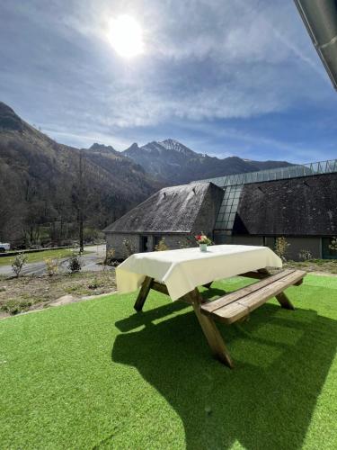 une table de pique-nique sur une pelouse avec un bâtiment dans l'établissement Le gite d'Aste, à Arrens-Marsous