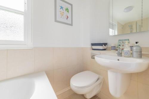 a white bathroom with a toilet and a sink at Jubilee Cottage in Whitstable