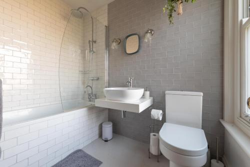 a white bathroom with a sink and a toilet at Fig Tree Cottage in Whitstable