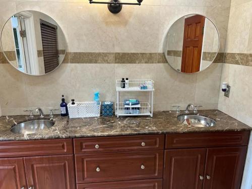 a bathroom with two sinks and two mirrors at Cozy lakeside suite with private bath & entrance in Pembroke Pines