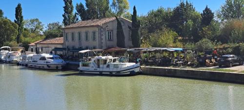 three boats docked in the water in front of a building at La Vernassonne in Alzonne