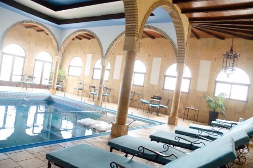 una piscina en un edificio con mesas y sillas en Hotel Balneario de Marmolejo, en Marmolejo