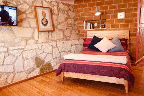 uma cama num quarto com uma parede de pedra em Suite Campestre Real del Monte em Mineral del Monte