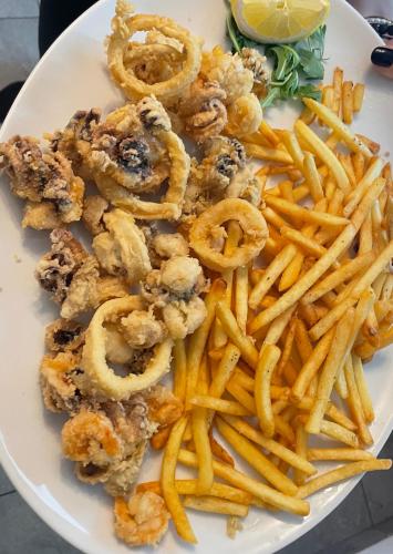 a plate of food with onion rings and french fries at HOTEL. RISTORANTE. DELLA POSTA CAMA in Cama
