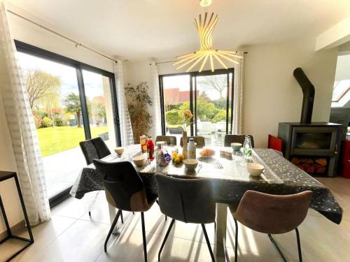 une salle à manger avec une table, des chaises et un lustre dans l'établissement Maison récente proche Caen et plages, à Bénouville