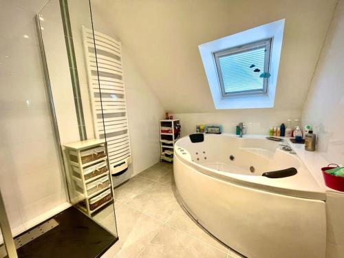 une salle de bain avec une grande baignoire et une fenêtre dans l'établissement Maison récente proche Caen et plages, à Bénouville