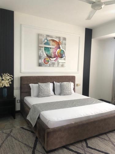 達累斯薩拉姆的住宿－4 Bedroom Duplex In Dar es salaam，卧室配有一张床,墙上挂有绘画作品