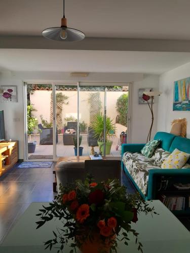 un salon avec un canapé et une table avec des fleurs dans l'établissement Charmant appartement - Golfe de Saint Tropez - Cogolin, à Cogolin