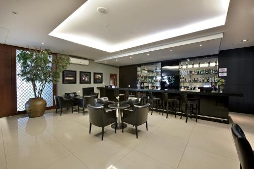 a restaurant with a bar with tables and chairs at Hotel Mont Blanc Premium in Ribeirão Preto