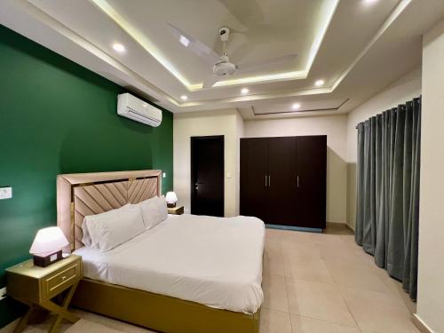 a bedroom with a white bed and a green wall at Serenity Corner 4 BHK in Islamabad