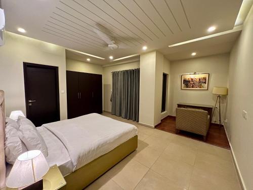 a bedroom with a large white bed and a desk at Serenity Corner 4 BHK in Islamabad