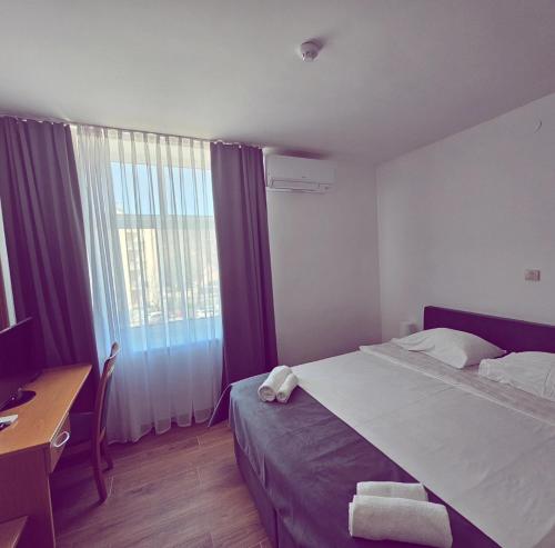 a bedroom with a bed and a desk and a window at Hotel Tabor in Sežana